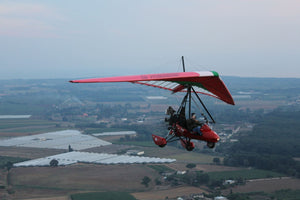 A POLARIS MOTOR TANDEM SEATER TRIKE WITH JUST THE PILOT ABOARD WEARING A CREWNECK UNDER A HEAVY WINDBREAKER AND HELMET