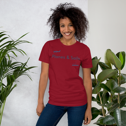 Pilots and mariners clothing: On a cardinal coloured tee shirt a navy blue low wing single engine plane is printed on the right breast whereas there is a sailing boat below the left breast with the phrase planes and sails written inbetween the two.