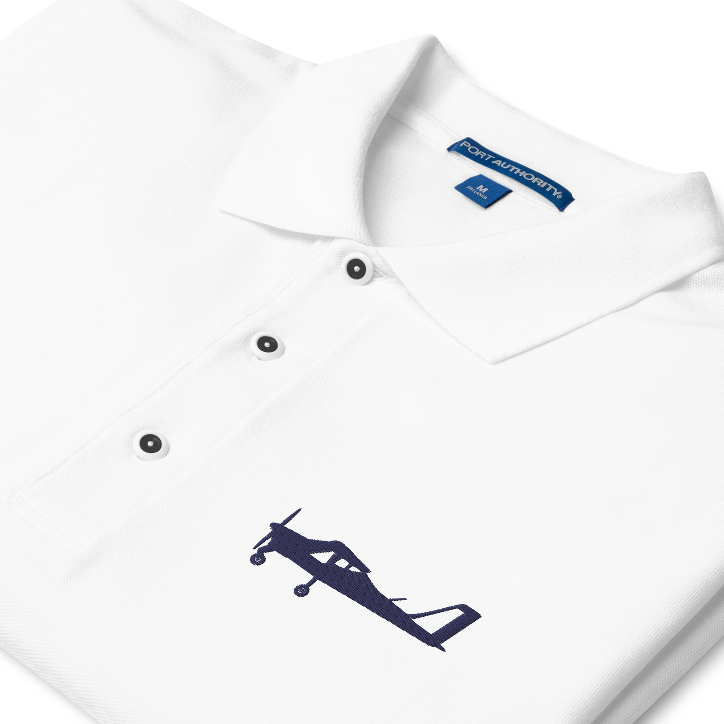 Navy blue Tecnam P92 aircraft embroidered design placed on the left breast of a white polo shirt.